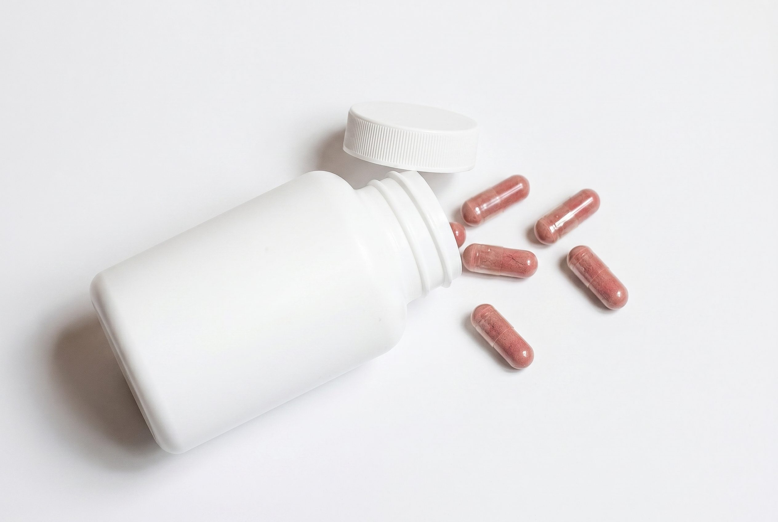 Bulk product image generation paid social flat lay with pink supplement capsules
