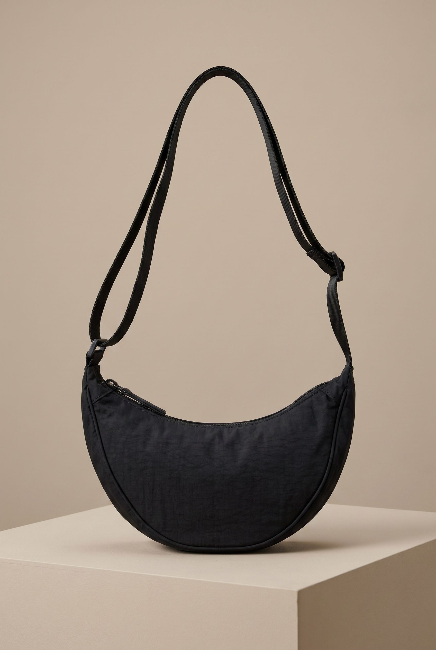 Bags product photography studio example of a black crescent shoulder bag with its strap fully visible