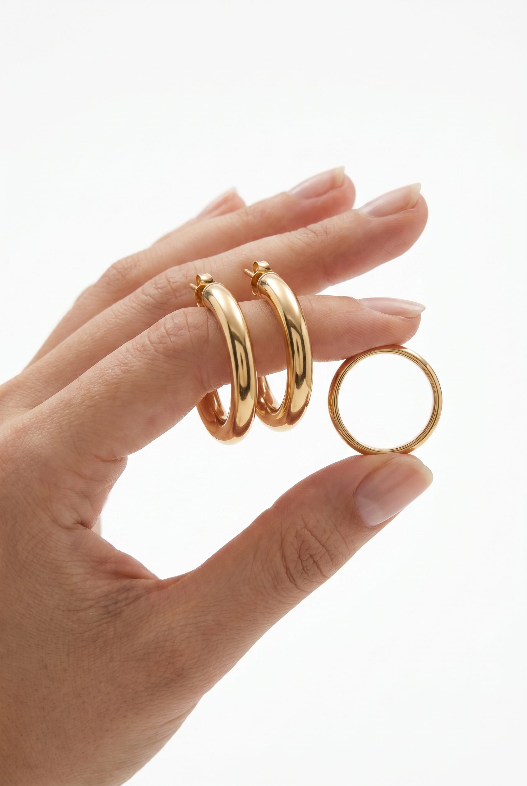 Gold hoop earrings and ring held in hands for an AI product image generator jewelry example.