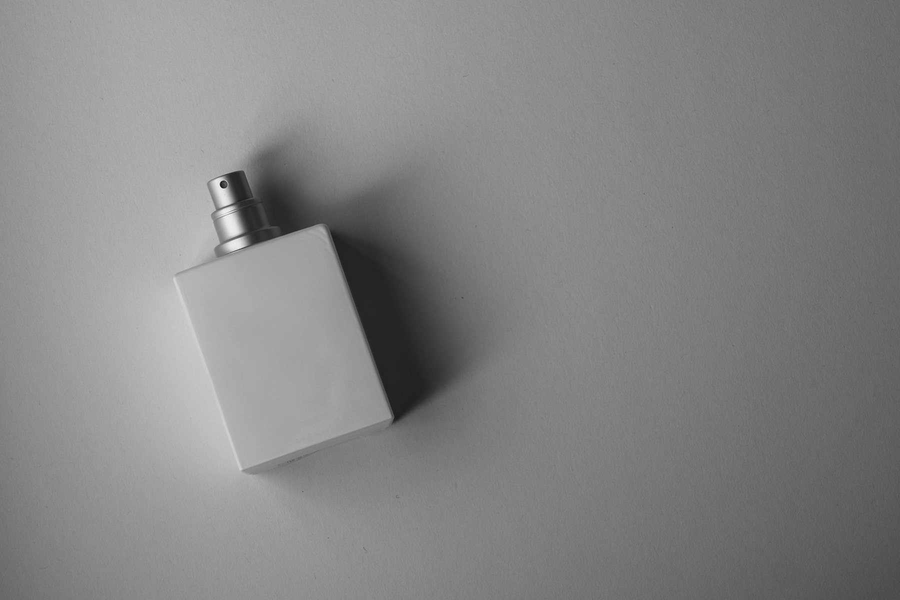 AI Background Generator for Product Photos before image showing brandless white perfume bottle for editorial surface