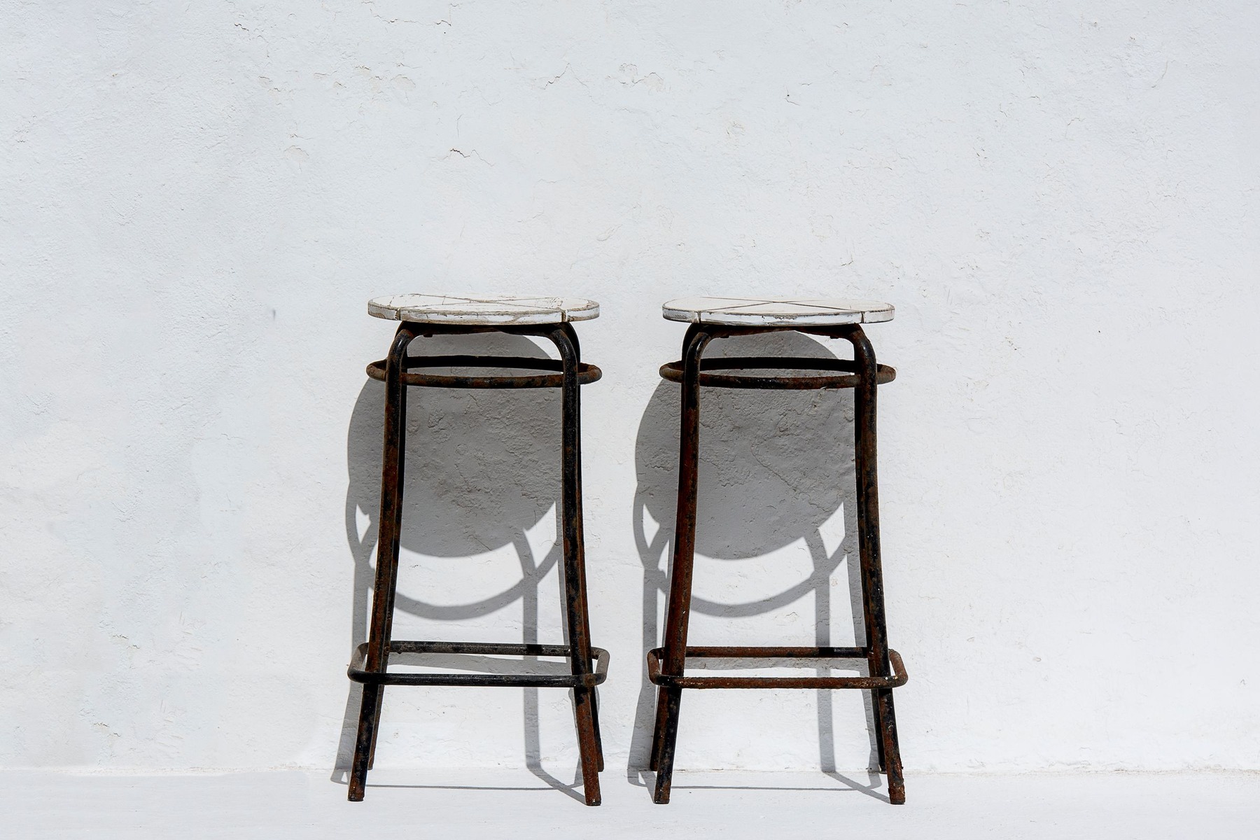 AI Product Photos for Ads before image showing two vintage stools against a white wall for side table campaign