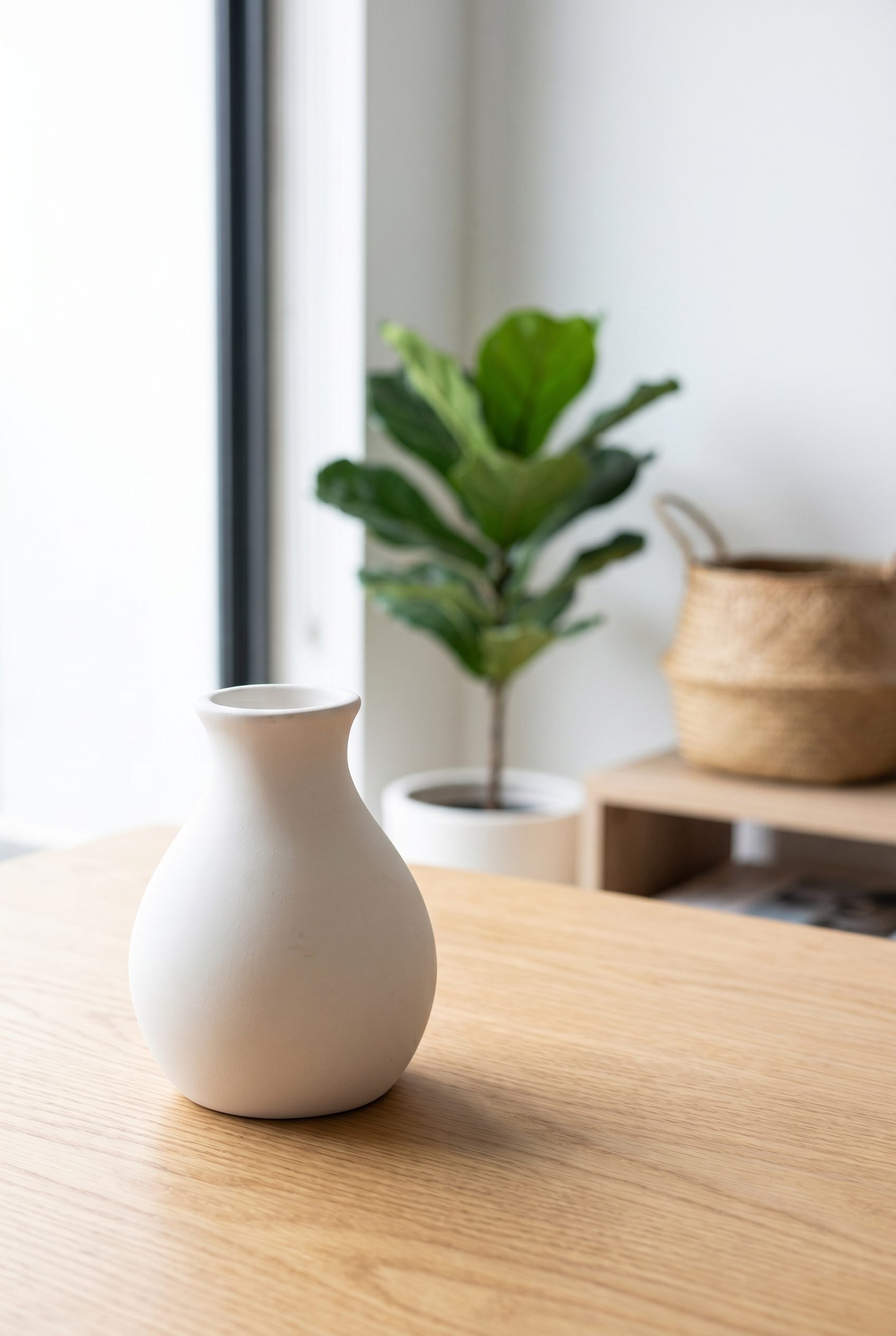 White ceramic vase staged on a bright home table for home goods product photography.