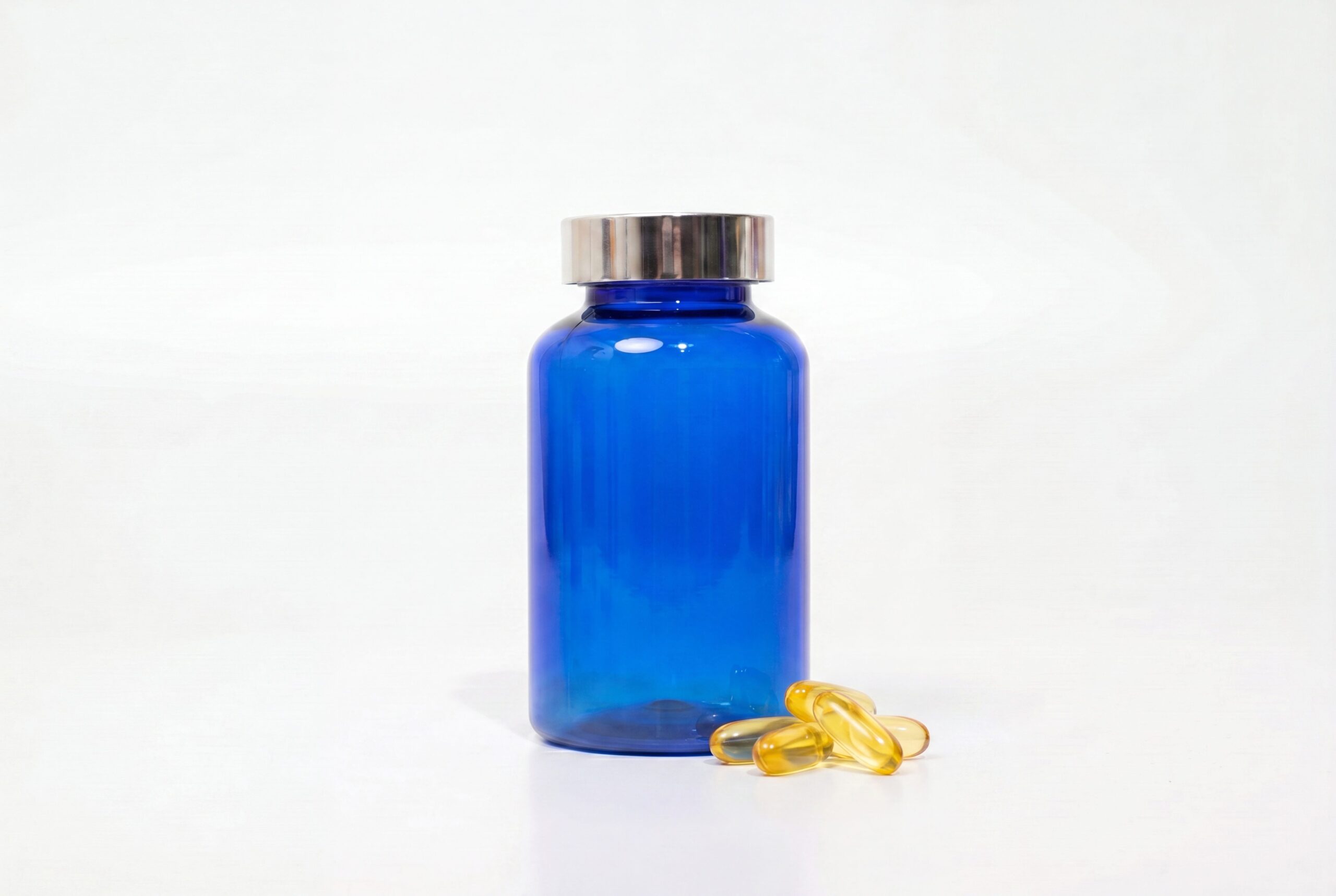 Supplement product photography audience image with a logo-free blue bottle and capsules