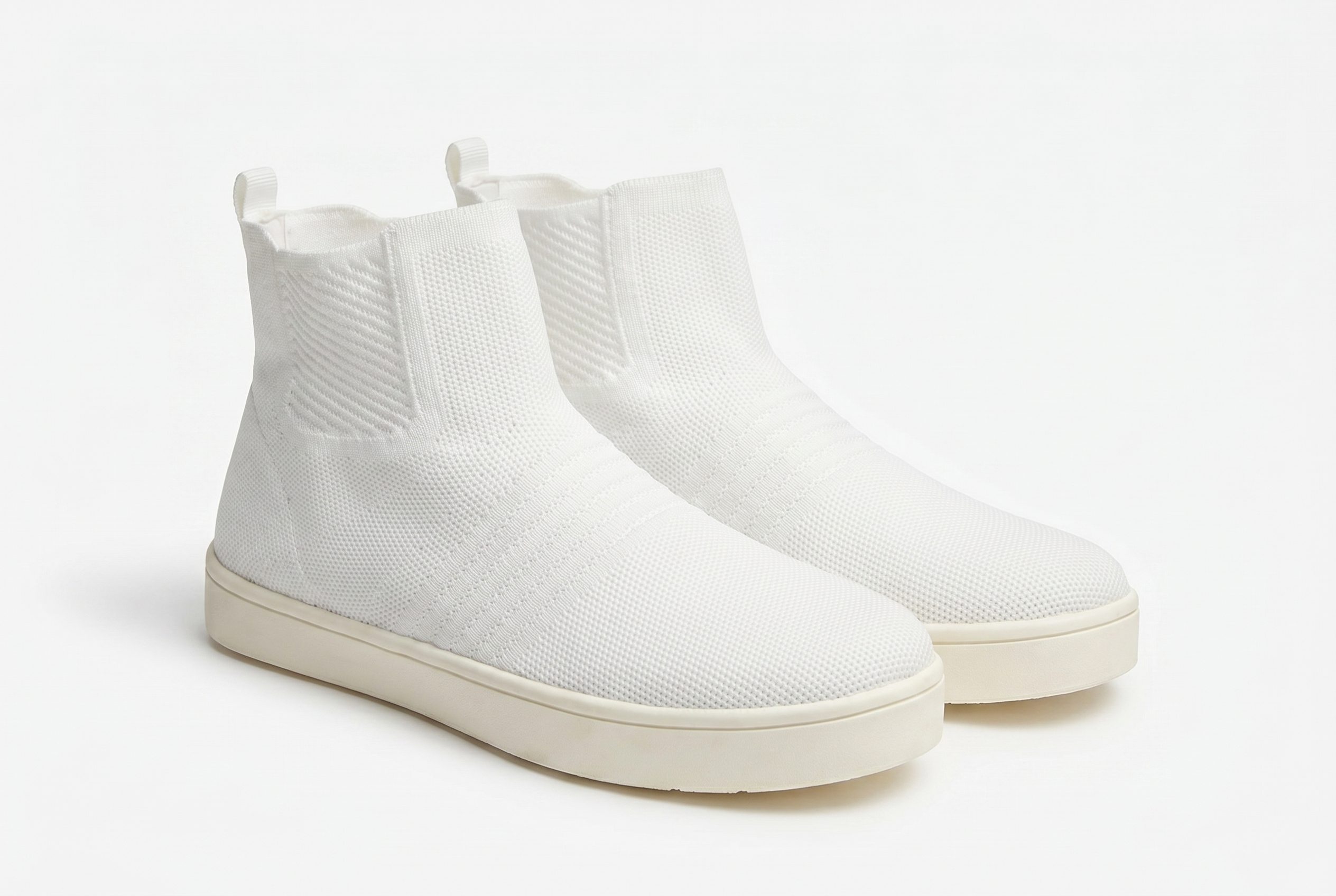 White knit sneakers on a neutral background for product page imagery