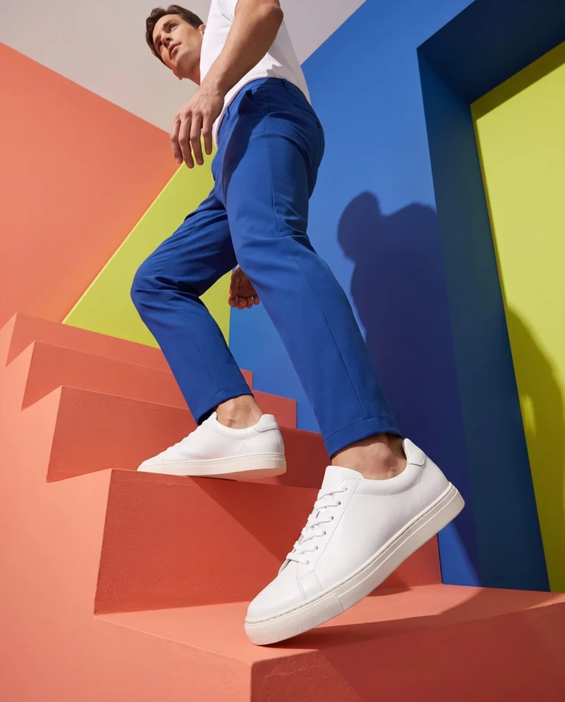 White sneakers worn on coral and cobalt architectural steps