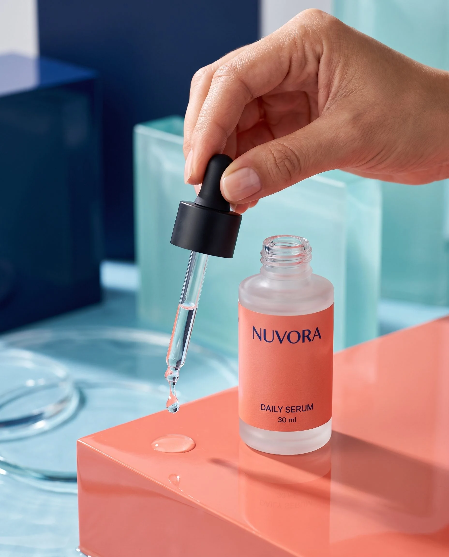 Frasco conta-gotas de sérum NUVORA posicionado sobre uma plataforma de coral.