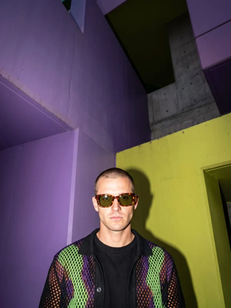 Adult man wearing tortoiseshell sunglasses in violet and lime architecture