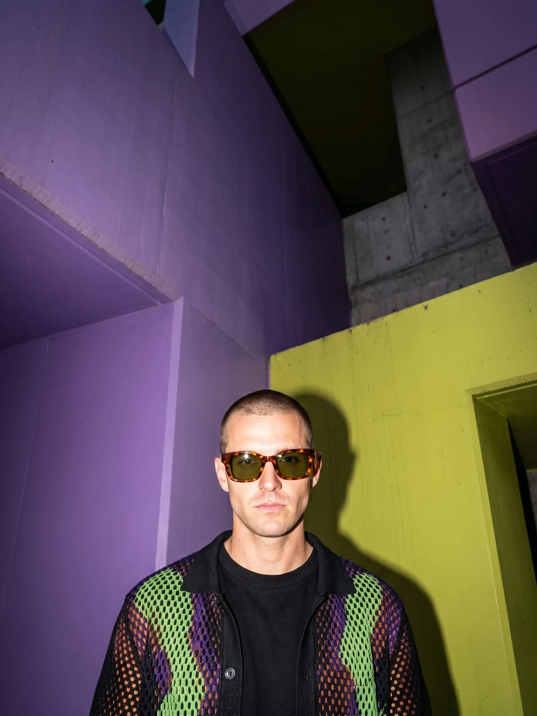 Adult man wearing tortoiseshell sunglasses in violet and lime architecture