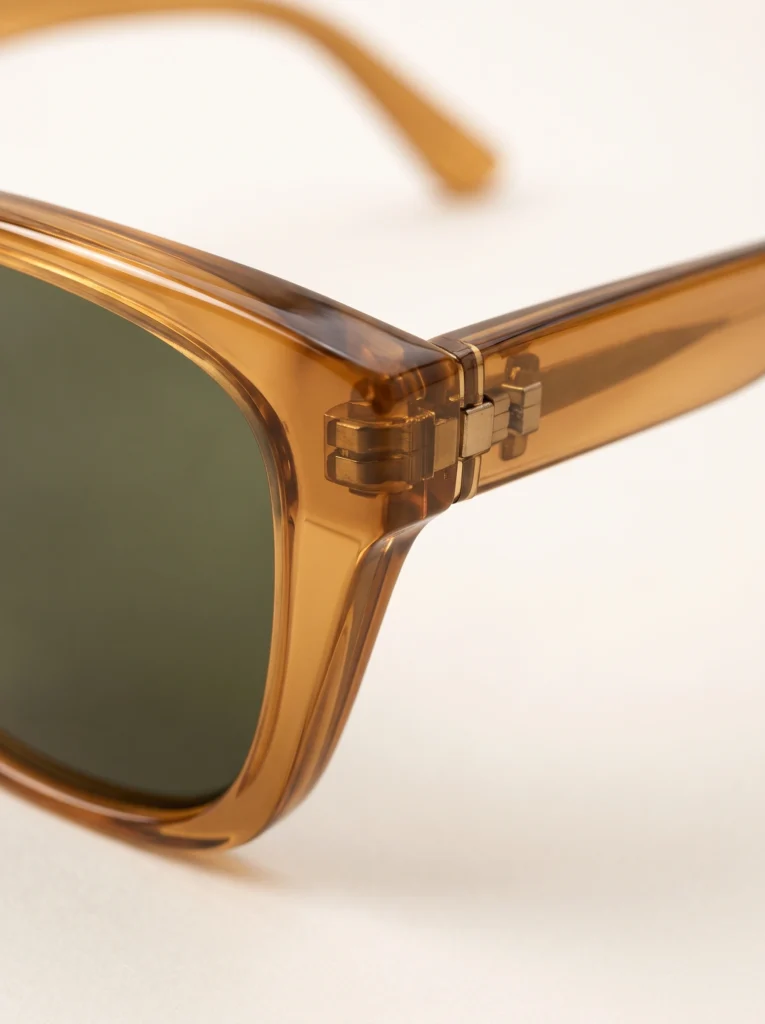 Amber sunglasses hinge and temple beside the olive lens corner.