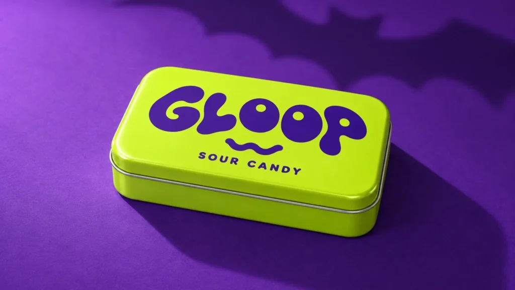 Green GLOOP candy tin on a purple surface with a crisp diagonal shadow and a bat-shaped background shadow